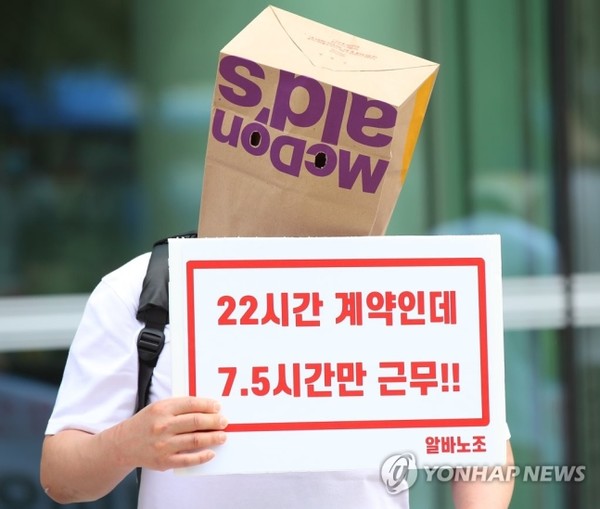 23일 오전 한국맥도날드 본사가 위치한 서울 종로구 종로타워 앞에서 열린 맥도날드의 근로계약 위반 고발 기자회견에서 한 참가자가 맥도날드 봉투를 쓴 채 피켓을 들고 있다. 사진=연합뉴스