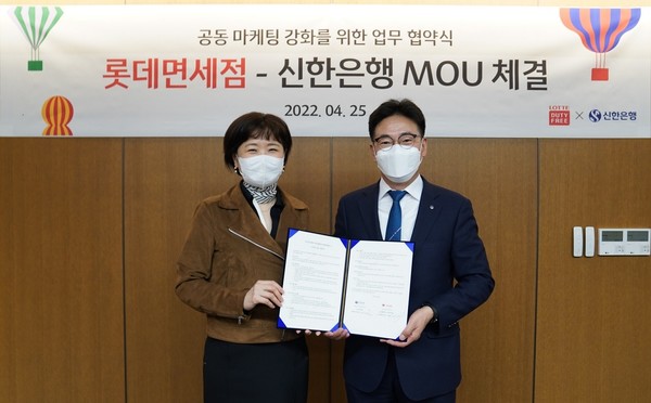 25일 서울시 중구 소재 롯데면세점 명동 본점에서 진행된 업무협약식에서 김민수 한은행 외환본부장이(오른쪽) 이상진 롯데면세점 케팅부문장과 기념촬영을 하고 있다./ 사진=신한은행