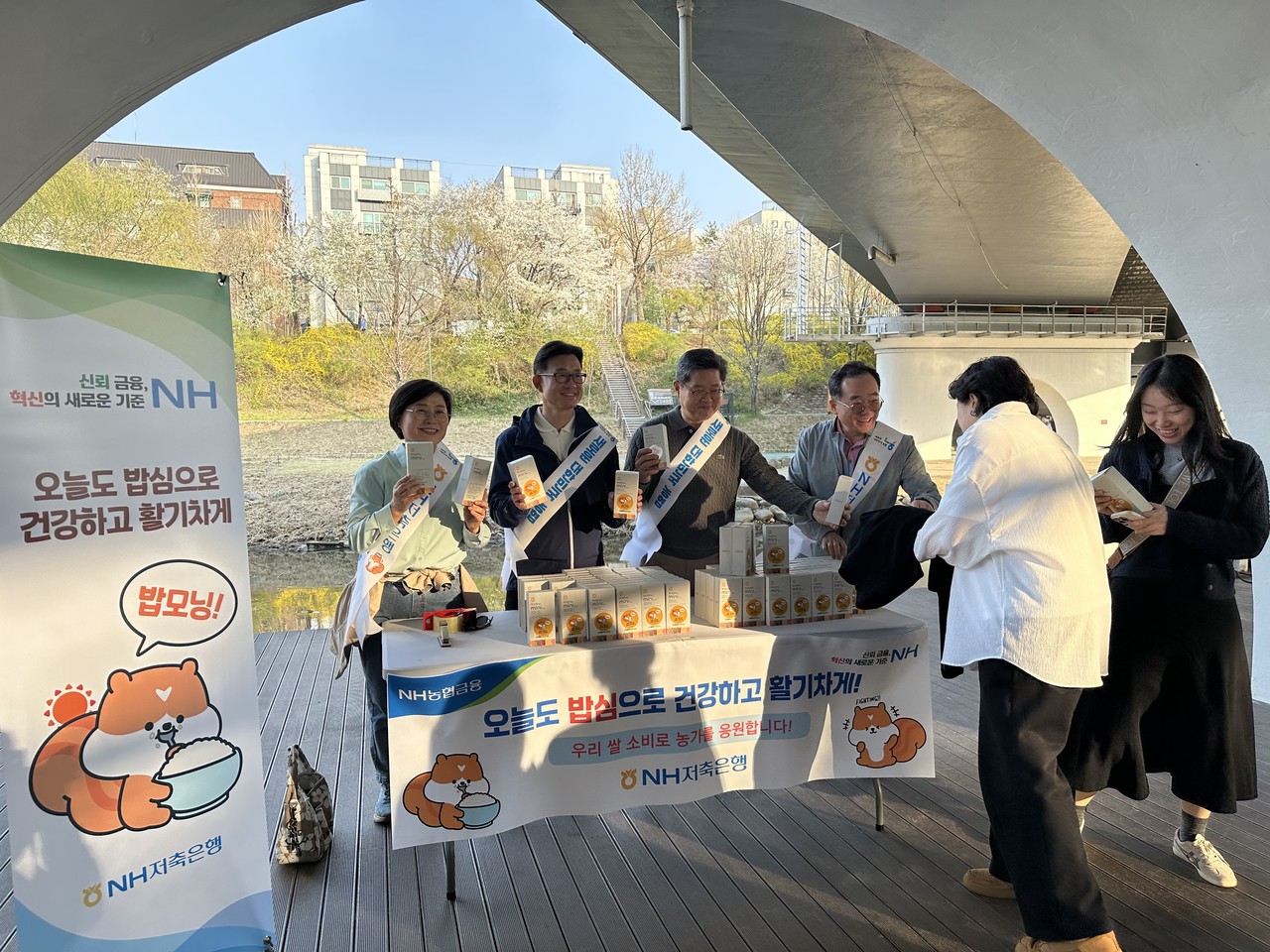  김장섭 NH저축은행 대표이사(왼쪽에서 네 번째)와 임직원들이 시민들에게 농협쌀을 나눠주고 있다. / 사진=NH저축은행