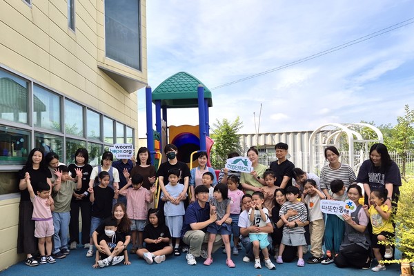 구미 하늘어린이집 원아와 교사가 '2025 리빙인하모니'로 개선된 외부놀이공간에 모여 있다./사진=우미건설