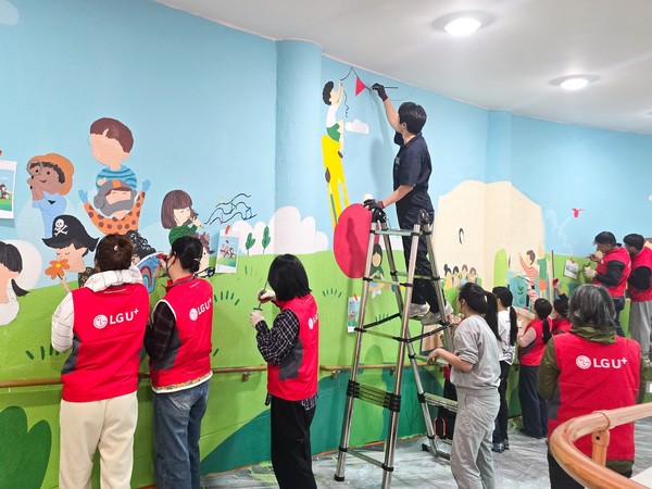 LG유플러스 임직원들이 충주성모학교 담장에 벽화를 그리고 있다./사진=LG유플러스